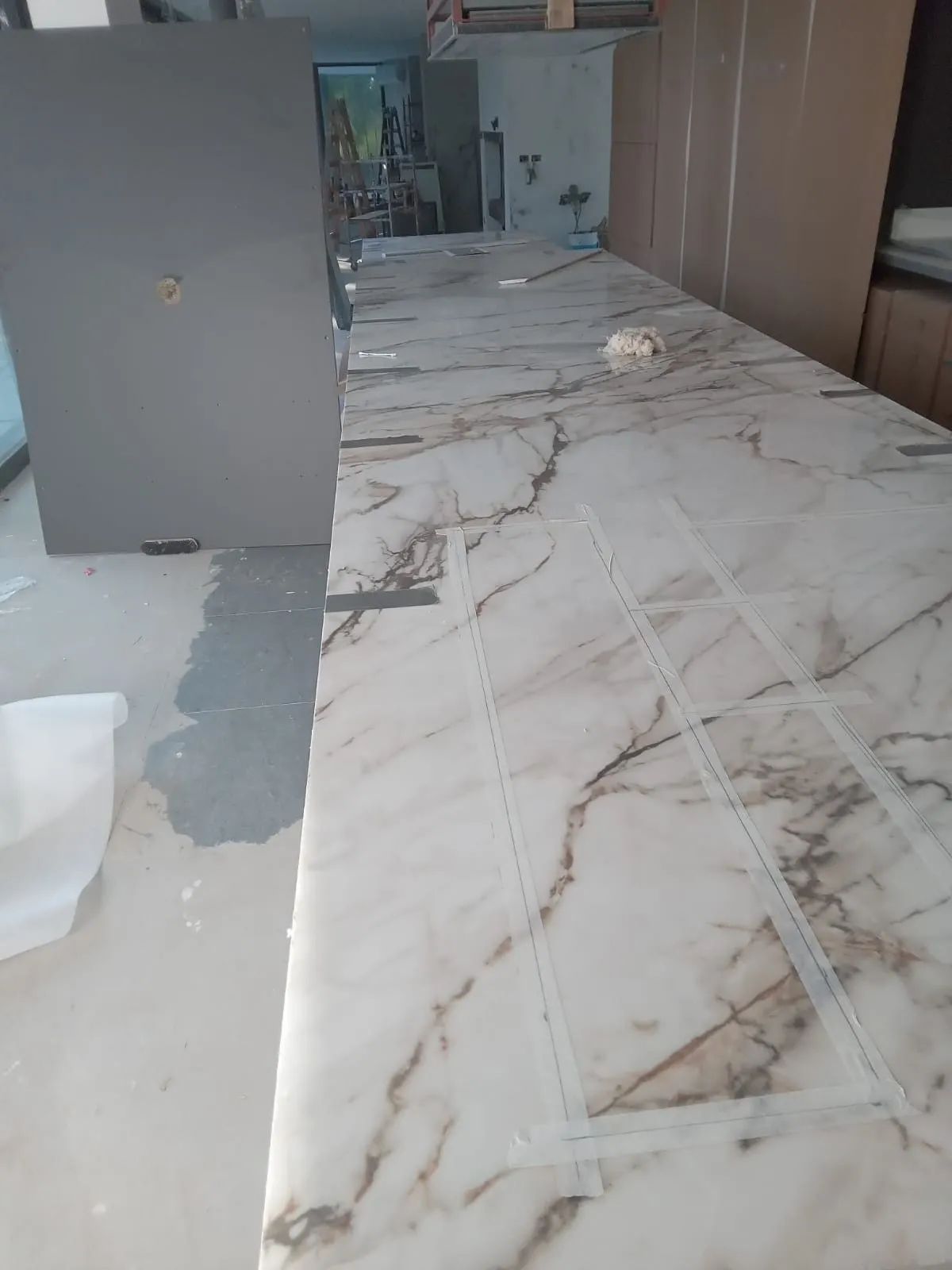 Encimera larga de porcelánico efecto mármol con vetas marrones, junto a los muebles