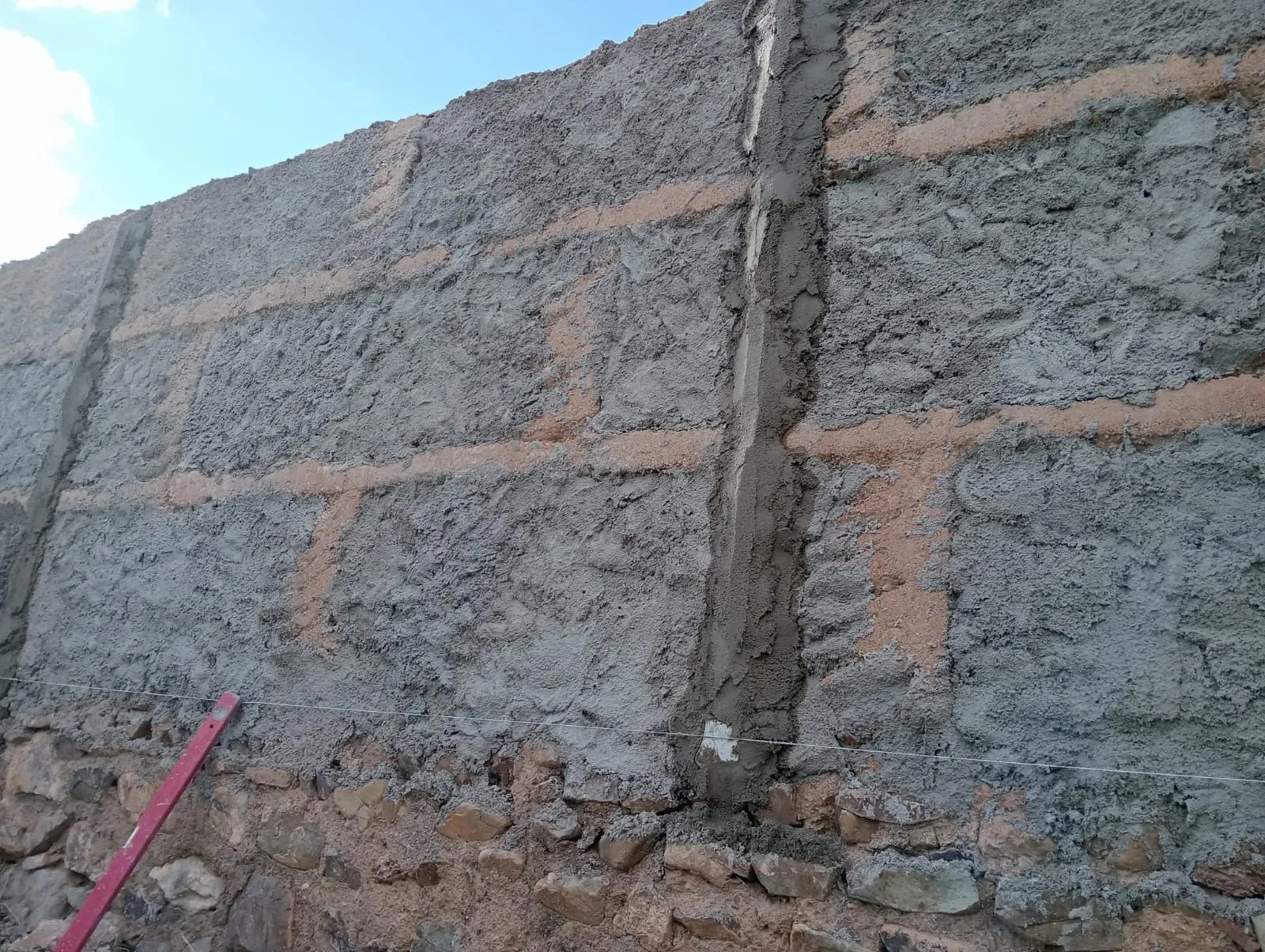 Muro de bloque y piedra con el mortero de revoco recién aplicado