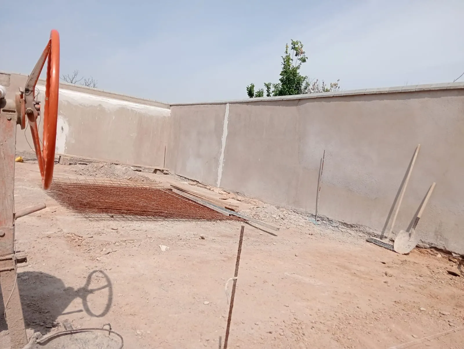 Patio en obra con muro de cerramiento revocado y mallazo preparado para la solera