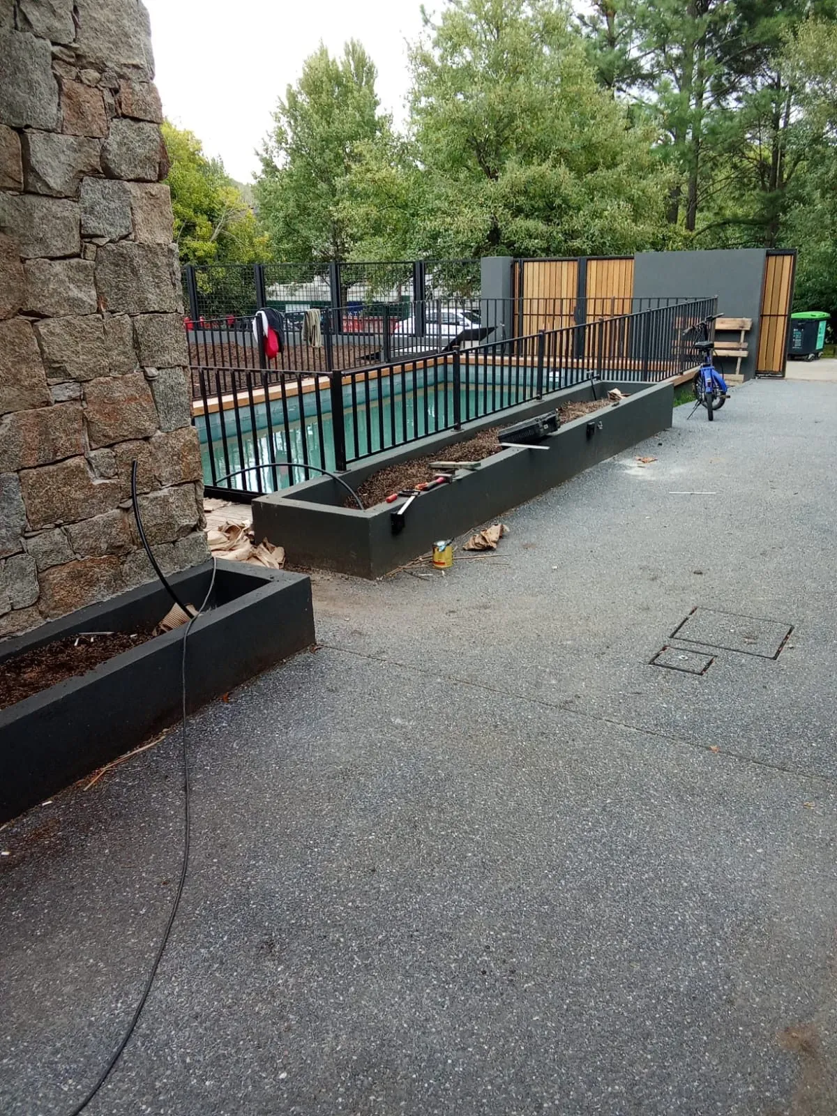 Valla de la piscina y jardineras junto a una pared de piedra natural